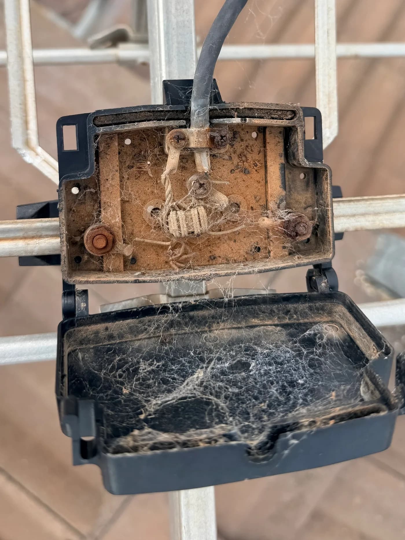 A corroded, cobwebbed antenna connection box that has let in water over time